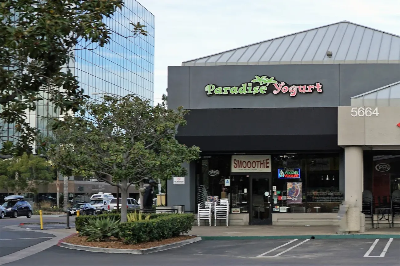 The Paradise Yogurt storefront in its Mission Valley plaza, with the green Paradise Yogurt sign and café chairs out front